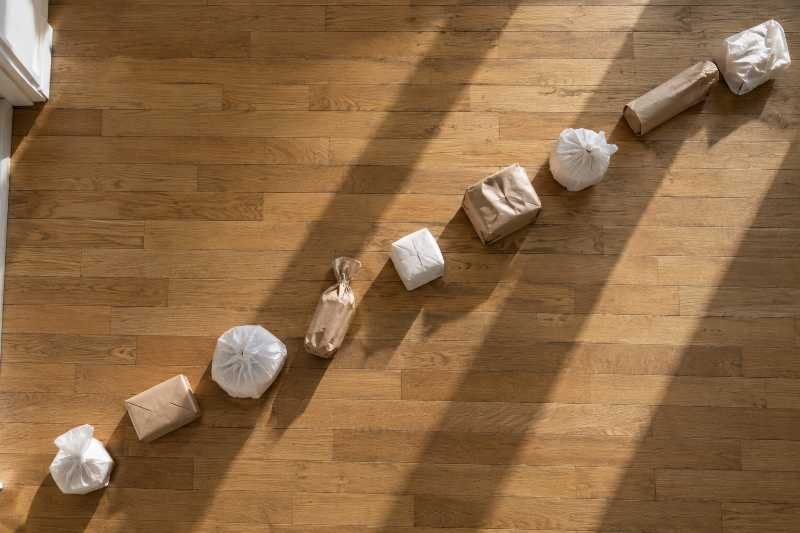 File d'objets emballés et espacés régulièrement sur un parquet nu